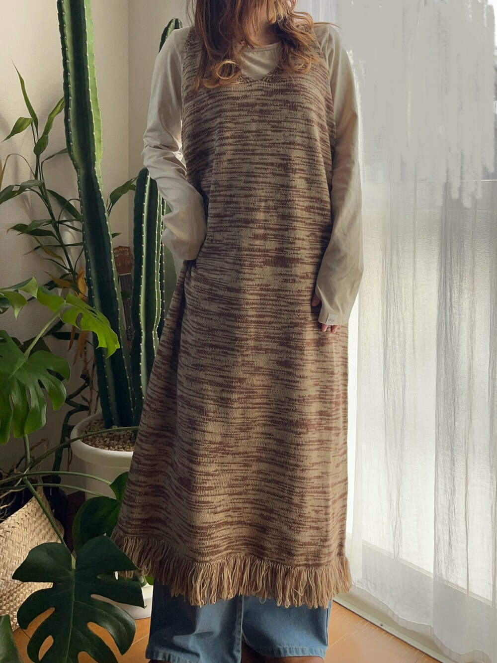 ブラウン系のワンピース、ベージュ系のTシャツ/カットソー、ブルー系のデニムパンツを着用したレディースの冬コーディネートの2枚目の写真