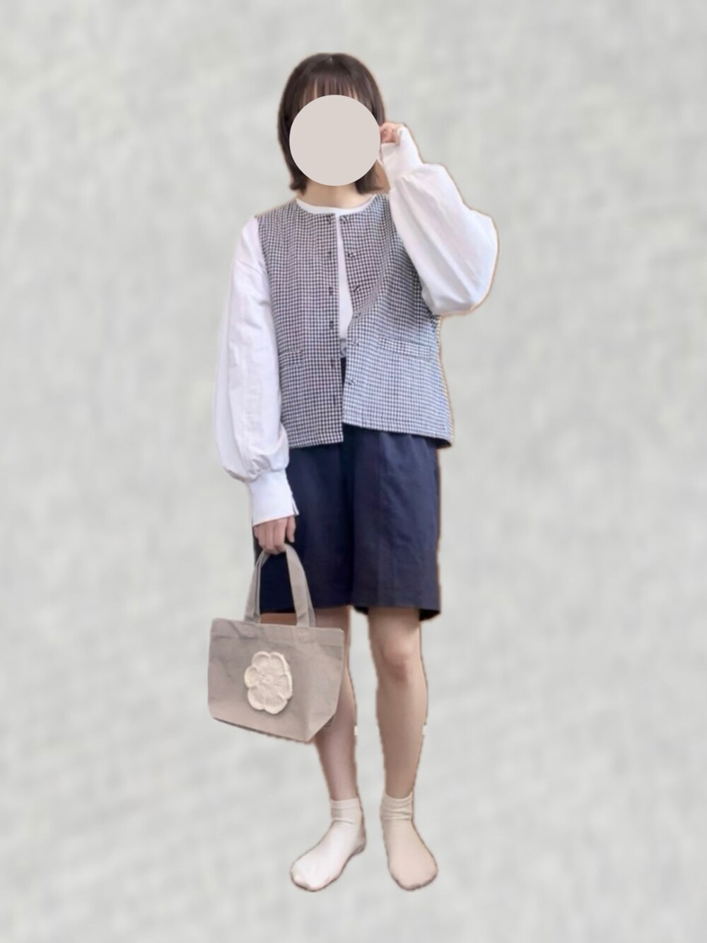 ブラック系のベスト、ホワイト系のTシャツ/カットソー、ベージュ系のハンドバッグを着用したレディースの春コーディネートの2枚目の写真