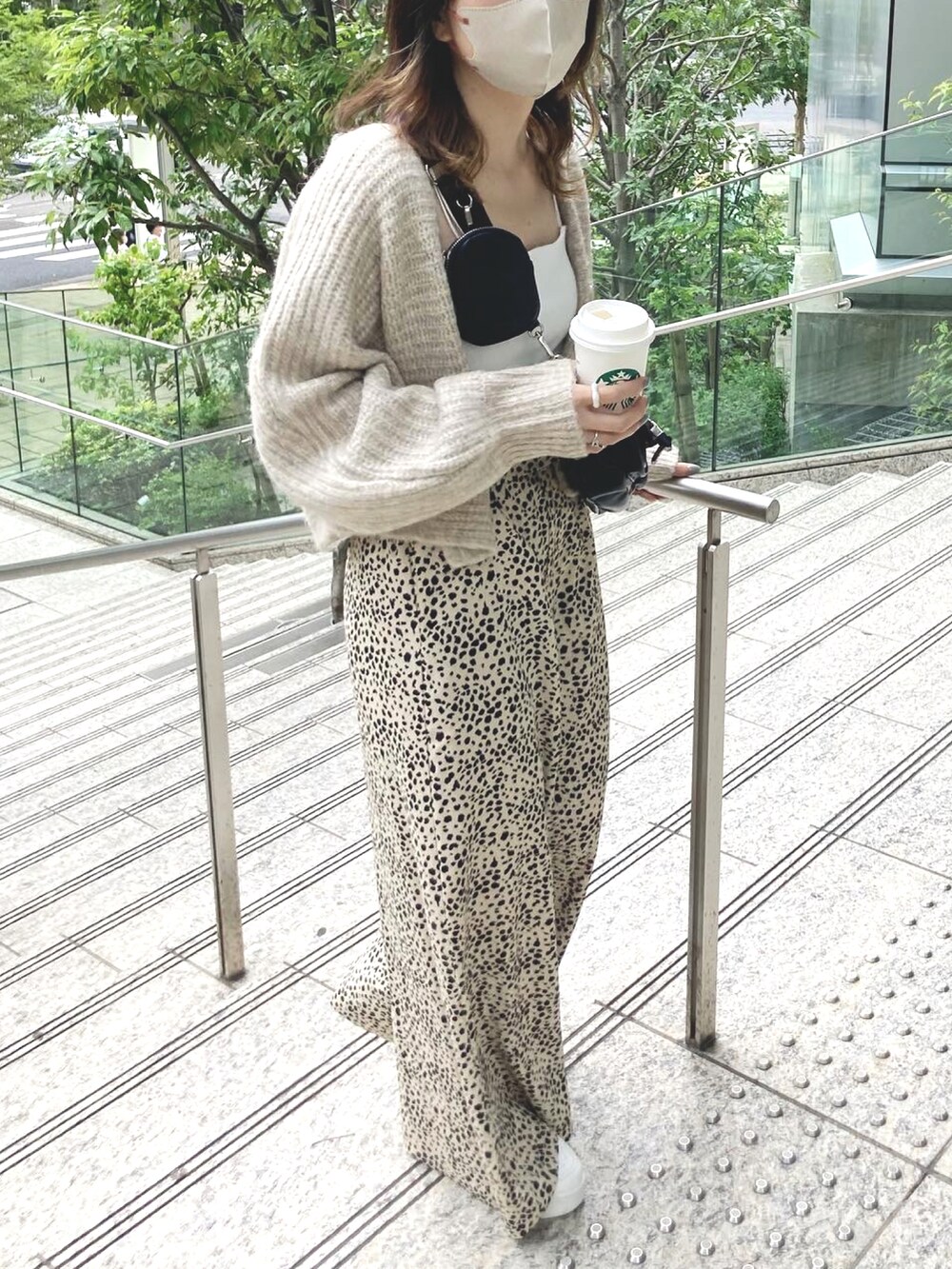 ベージュ系のカーディガン/ボレロ、ホワイト系のキャミソール、ブラック系のショルダーバッグを着用したレディースの夏コーディネートの2枚目の写真