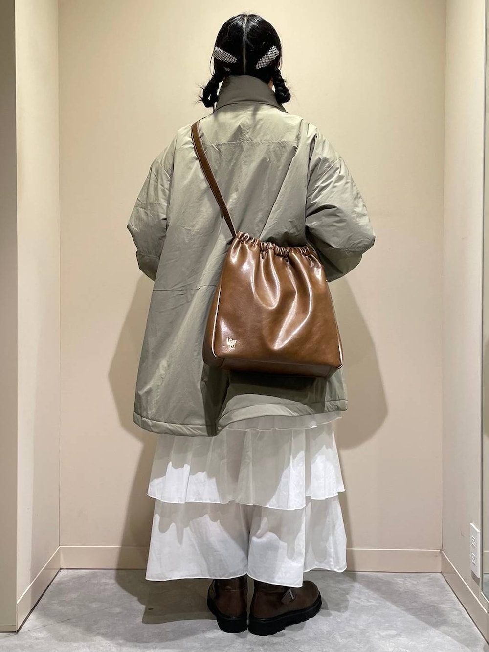 グリーン系のその他アウター、ブラウン系のブーツ、ホワイト系のスカートを着用したレディースの秋コーディネートの3枚目の写真