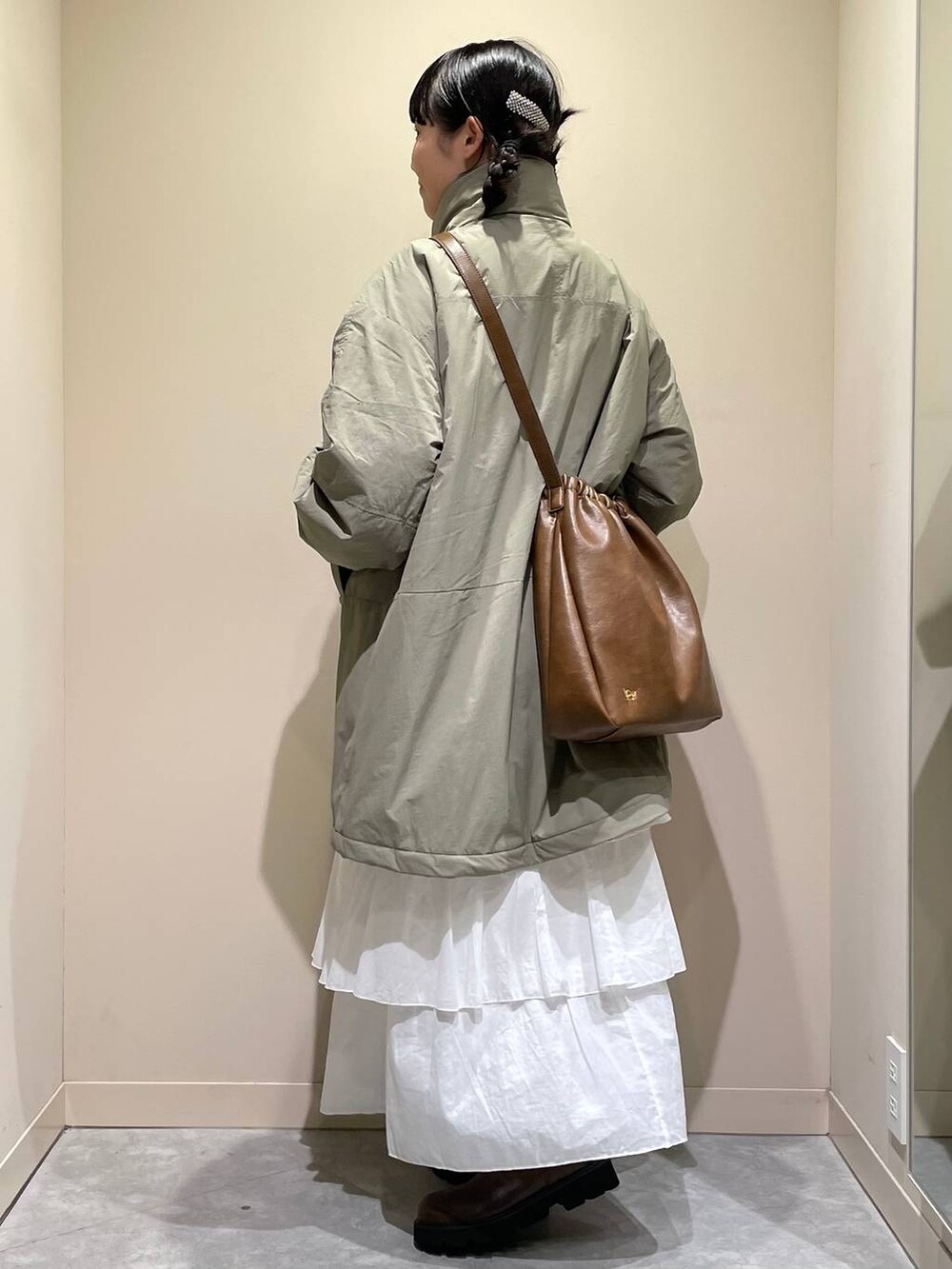 グリーン系のその他アウター、ブラウン系のブーツ、ホワイト系のスカートを着用したレディースの秋コーディネートの2枚目の写真