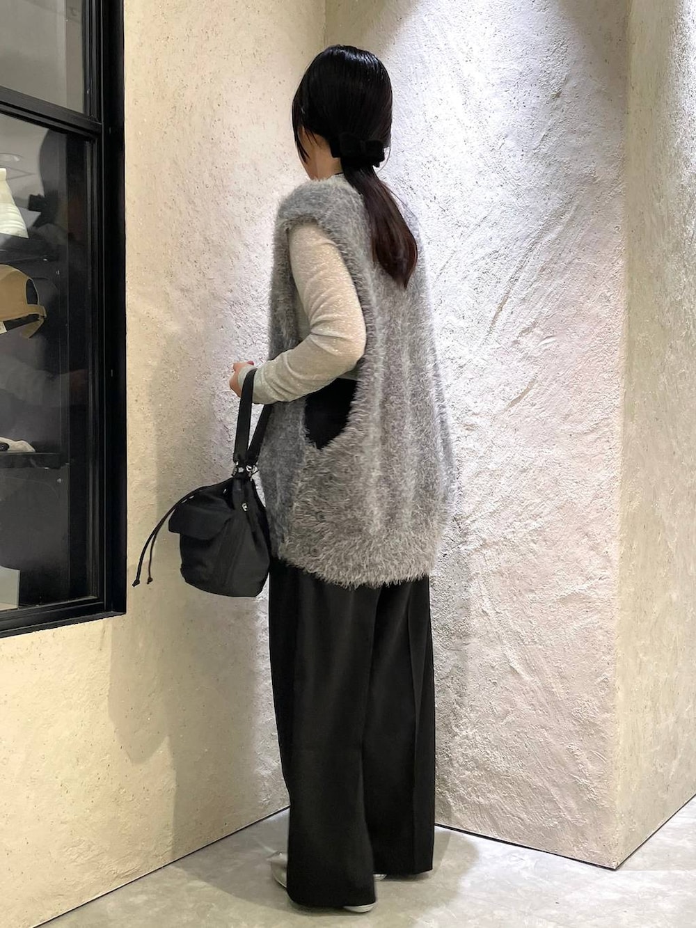ブラック系のスラックス、グレー系のベスト、ブラック系のショルダーバッグを着用したレディースの秋コーディネートの2枚目の写真