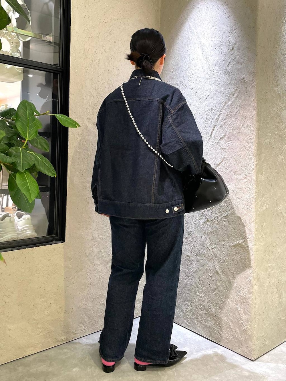 ブラック系のハンドバッグ、ブルー系のデニムパンツ、ブラック系のパンプスを着用したレディースの春コーディネートの5枚目の写真