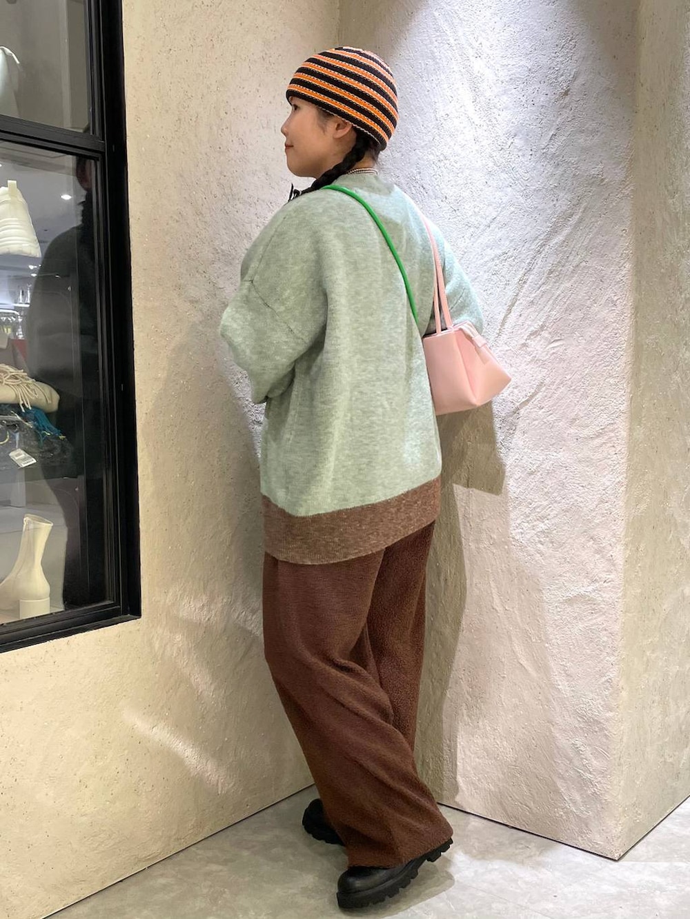 ブラック系のブーツ、ピンク系のショルダーバッグ、グリーン系のニット/セーターを着用したレディースの冬コーディネートの3枚目の写真