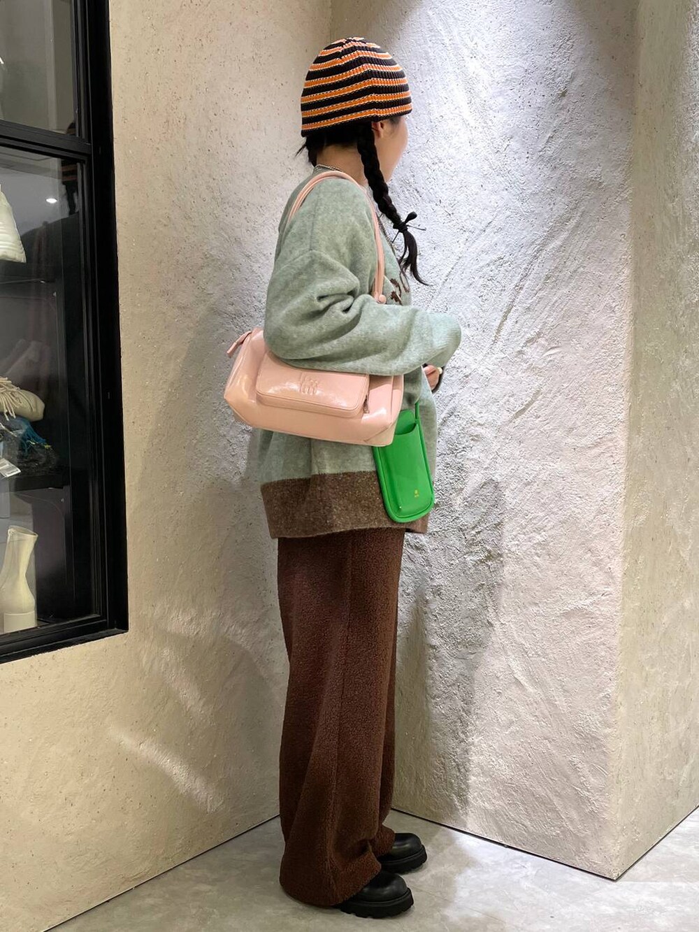 ブラック系のブーツ、ピンク系のショルダーバッグ、グリーン系のニット/セーターを着用したレディースの冬コーディネートの5枚目の写真
