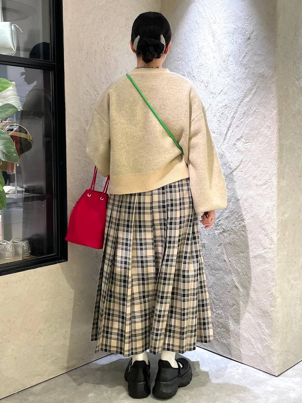 ブラウン系のチェスターコート、ブラック系のスニーカー、レッド系のハンドバッグを着用したレディースの秋コーディネートの7枚目の写真