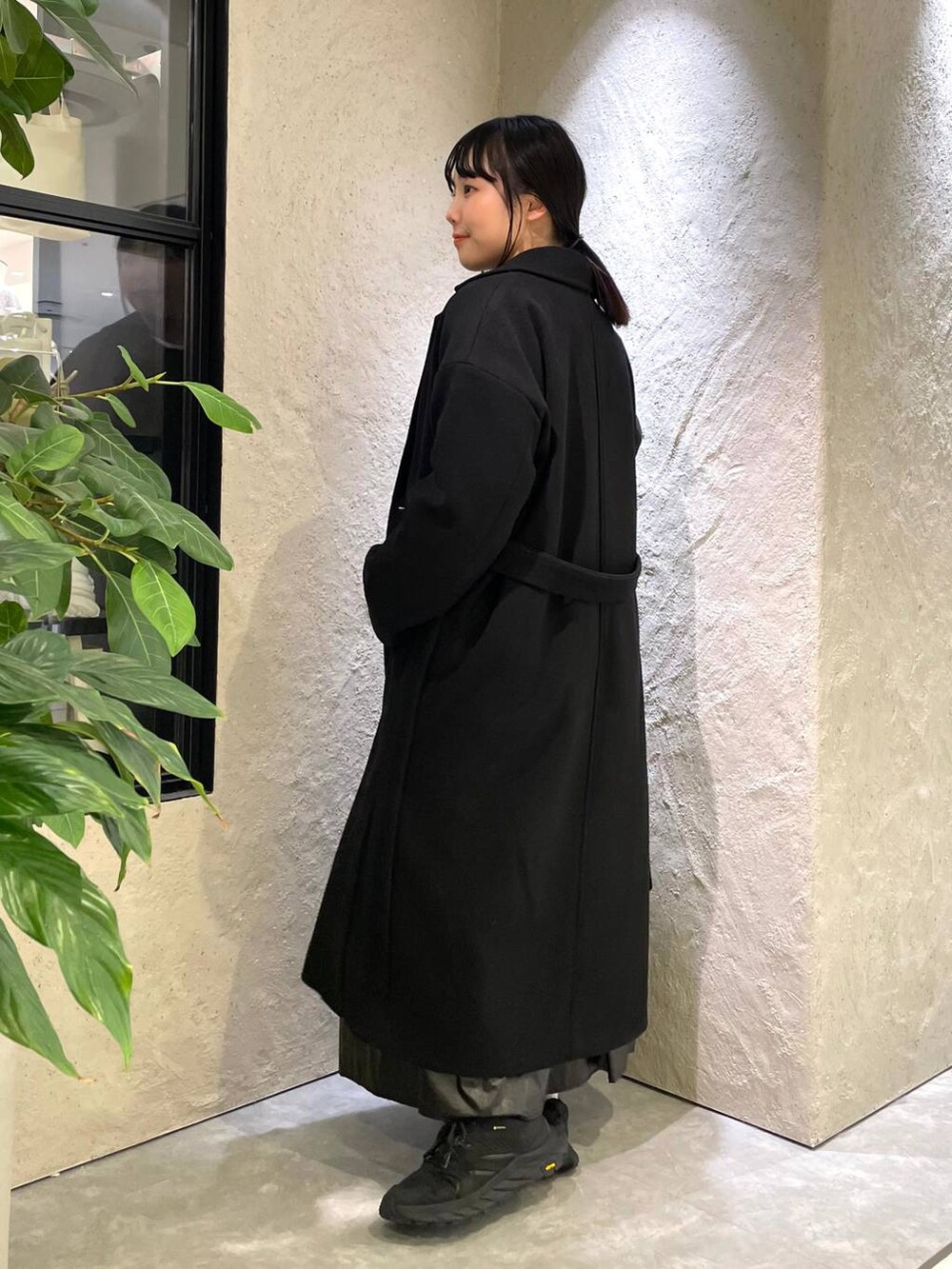 ブラック系のトレンチコート、ブラック系のTシャツ/カットソー、ブラック系のハンドバッグを着用したレディースの冬コーディネートの6枚目の写真