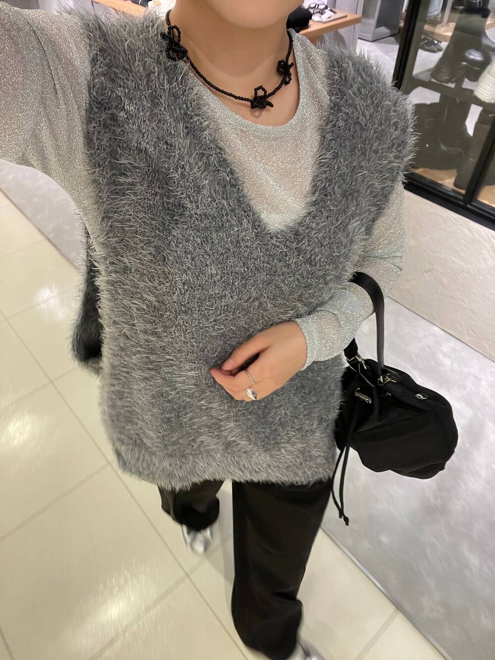 ブラック系のスラックス、グレー系のベスト、ブラック系のショルダーバッグを着用したレディースの秋コーディネートの5枚目の写真