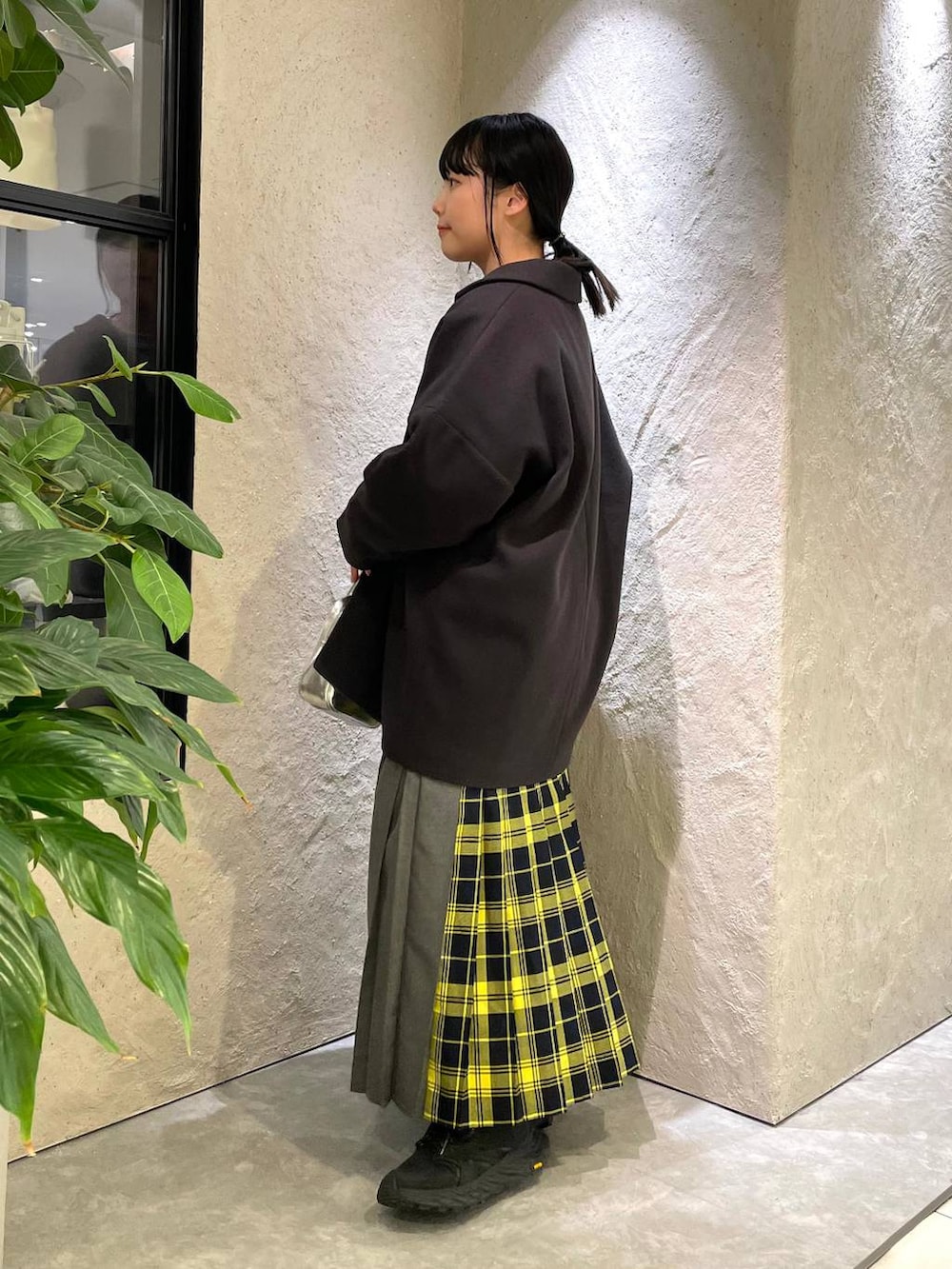 グレー系のステンカラーコート、グレー系のスウェット、イエロー系のスカートを着用したレディースの冬コーディネートの2枚目の写真