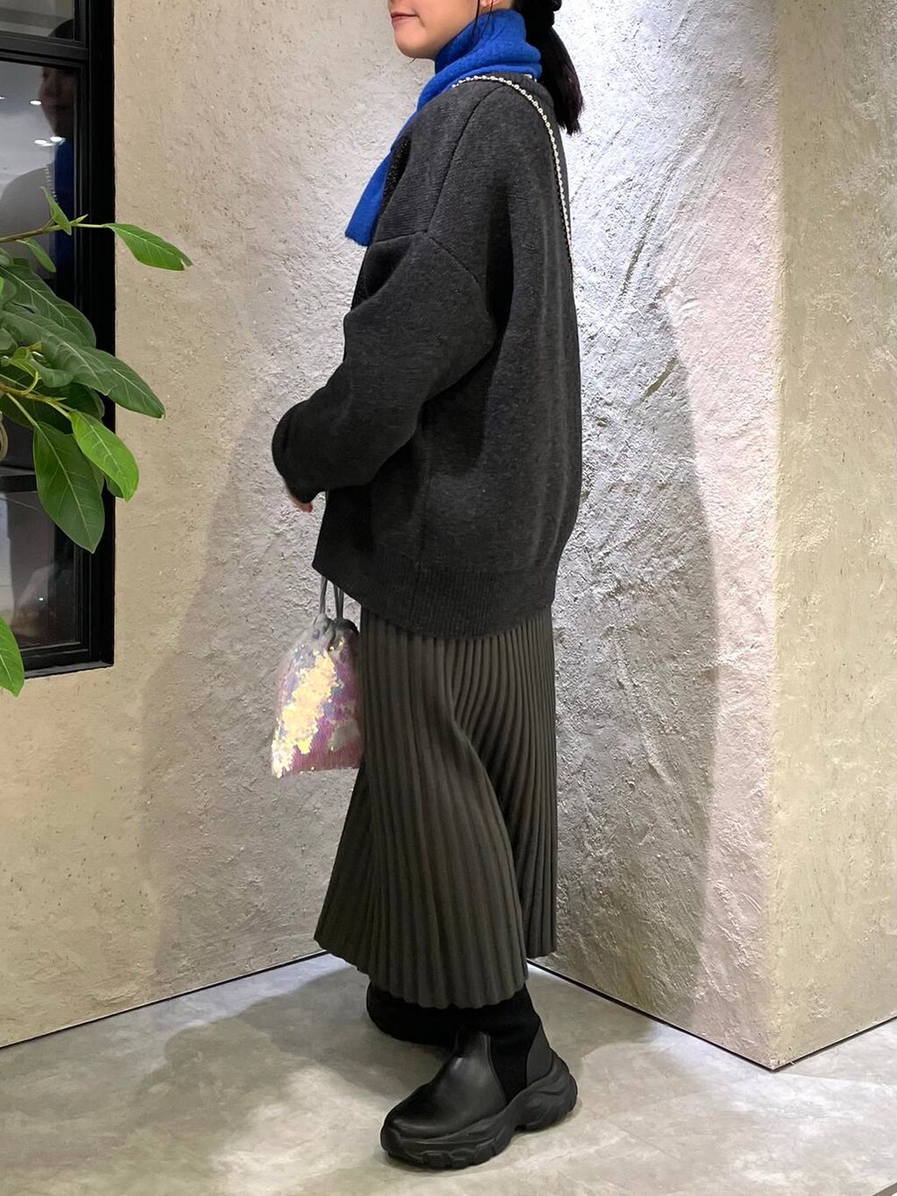 ホワイト系のハンドバッグ、グレー系のワンピース、ブラック系のブーツを着用したレディースの冬コーディネートの2枚目の写真