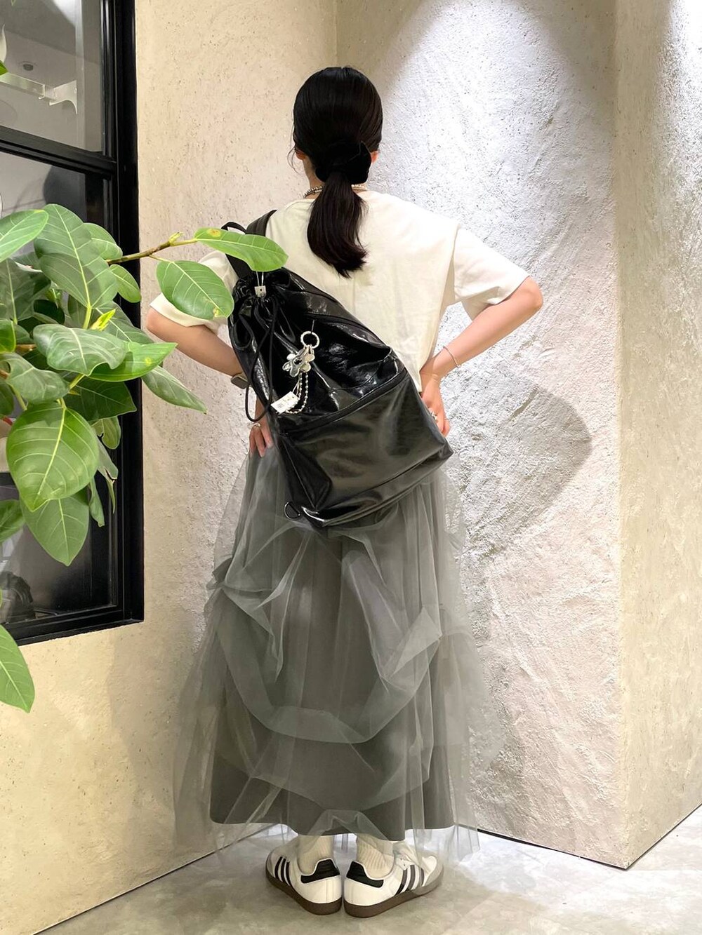 グレー系のスカート、ホワイト系のTシャツ/カットソー、ブラック系のショルダーバッグを着用したレディースの夏コーディネートの4枚目の写真