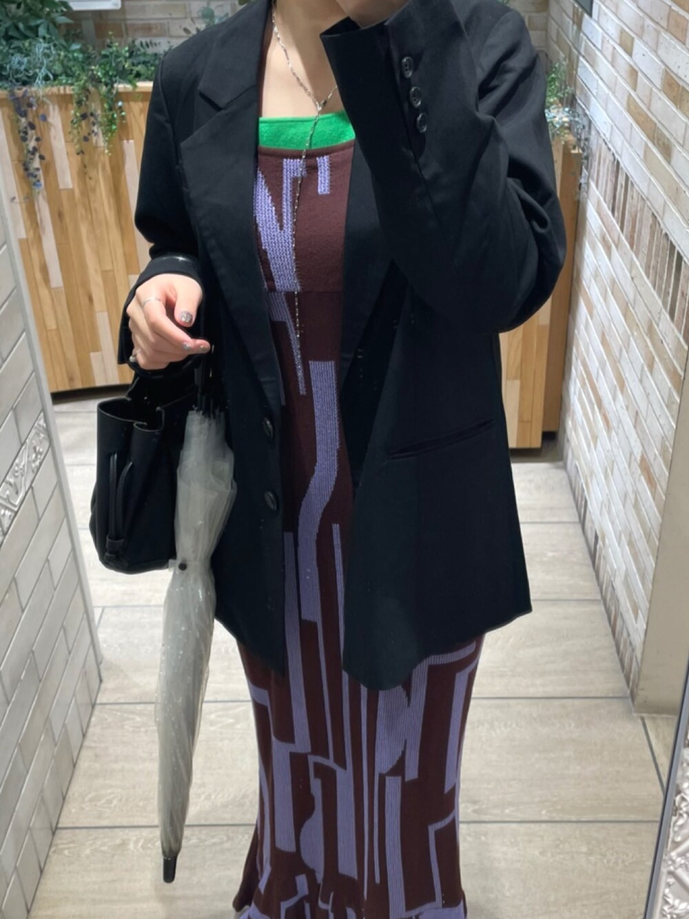 ブラック系のテーラードジャケット、パープル系のワンピース、グリーン系のタンクトップを着用したレディースの春コーディネートの2枚目の写真