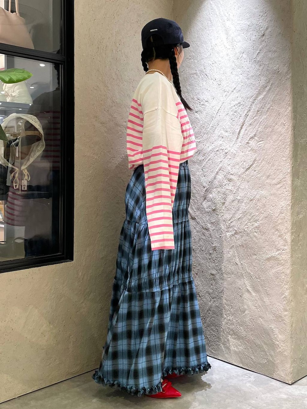 レッド系のパンプス、ピンク系のハンドバッグ、ブルー系のスカートを着用したレディースの秋コーディネートの4枚目の写真