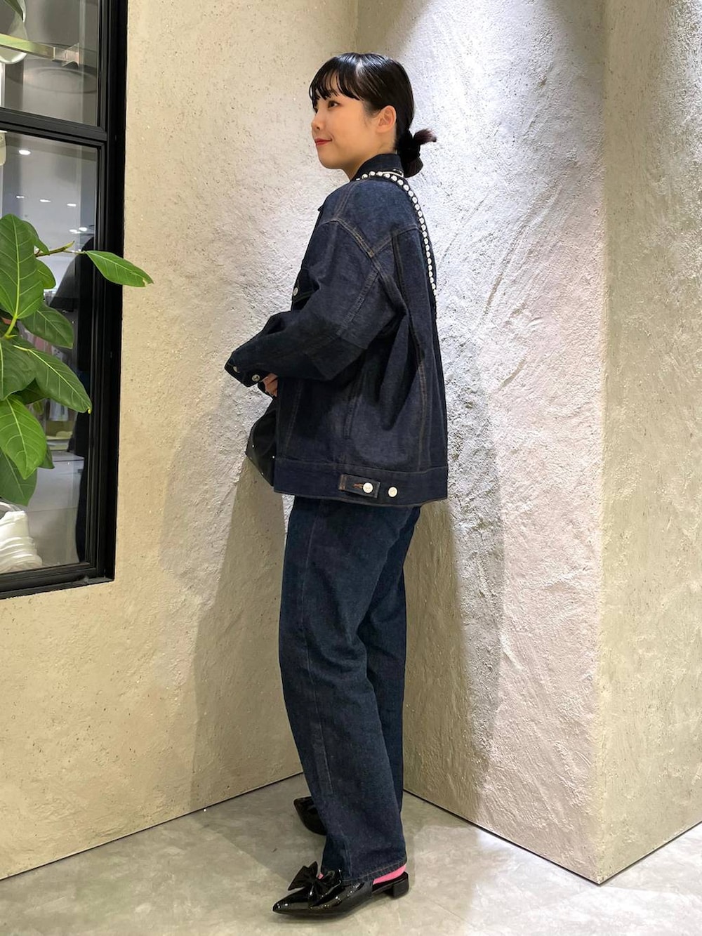 ブラック系のハンドバッグ、ブルー系のデニムパンツ、ブラック系のパンプスを着用したレディースの春コーディネートの4枚目の写真