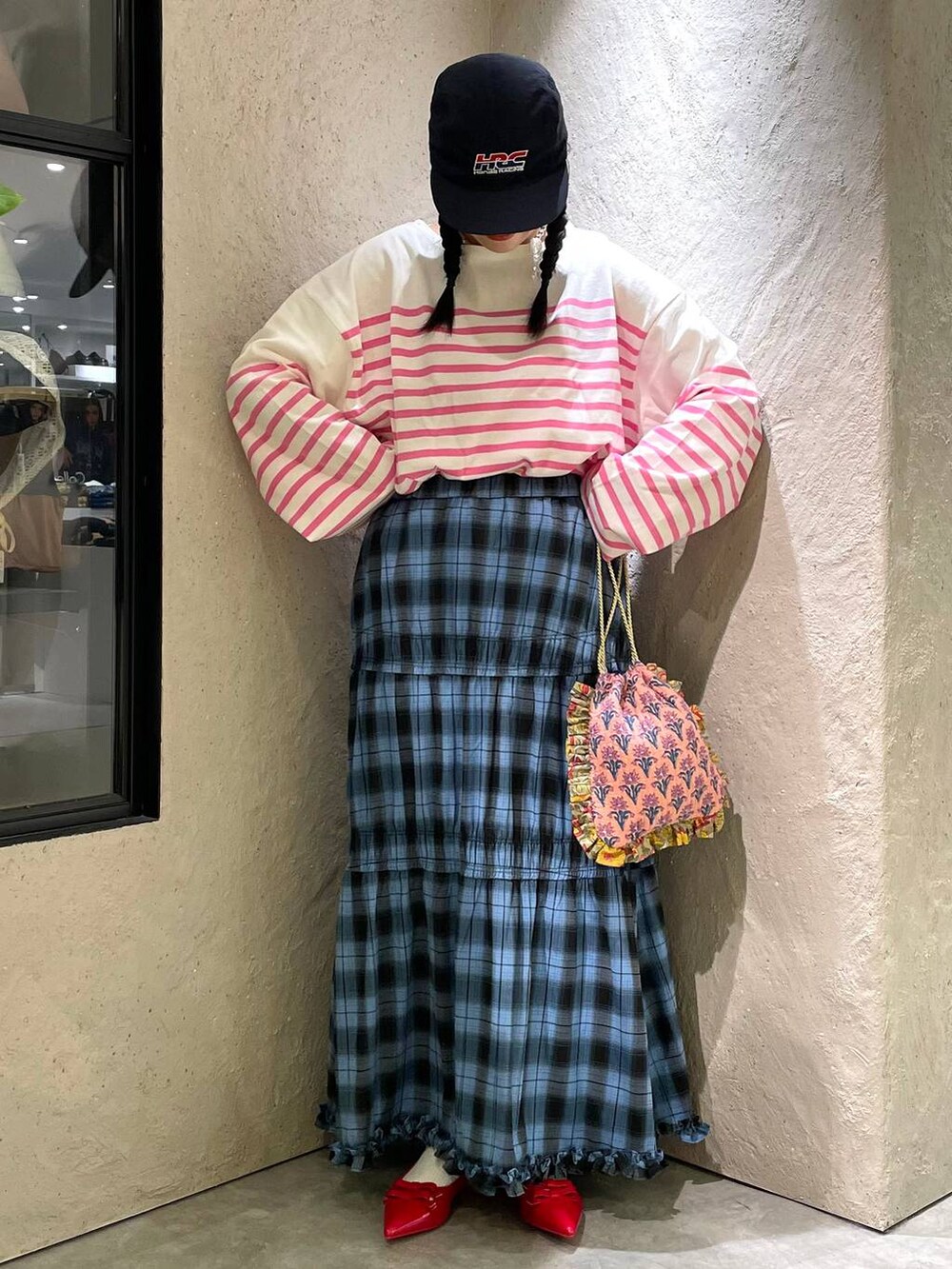 レッド系のパンプス、ピンク系のハンドバッグ、ブルー系のスカートを着用したレディースの秋コーディネートの5枚目の写真