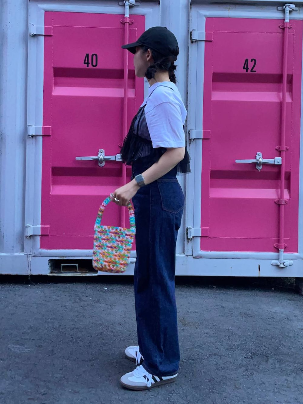 ホワイト系のスニーカー、ブラック系のベスト、ブルー系のデニムパンツを着用したレディースの夏コーディネートの2枚目の写真