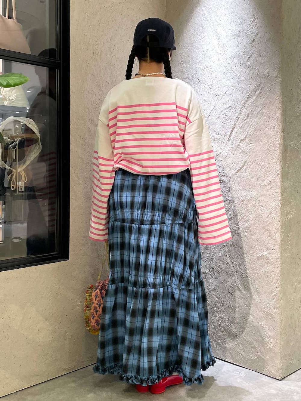 レッド系のパンプス、ピンク系のハンドバッグ、ブルー系のスカートを着用したレディースの秋コーディネートの3枚目の写真