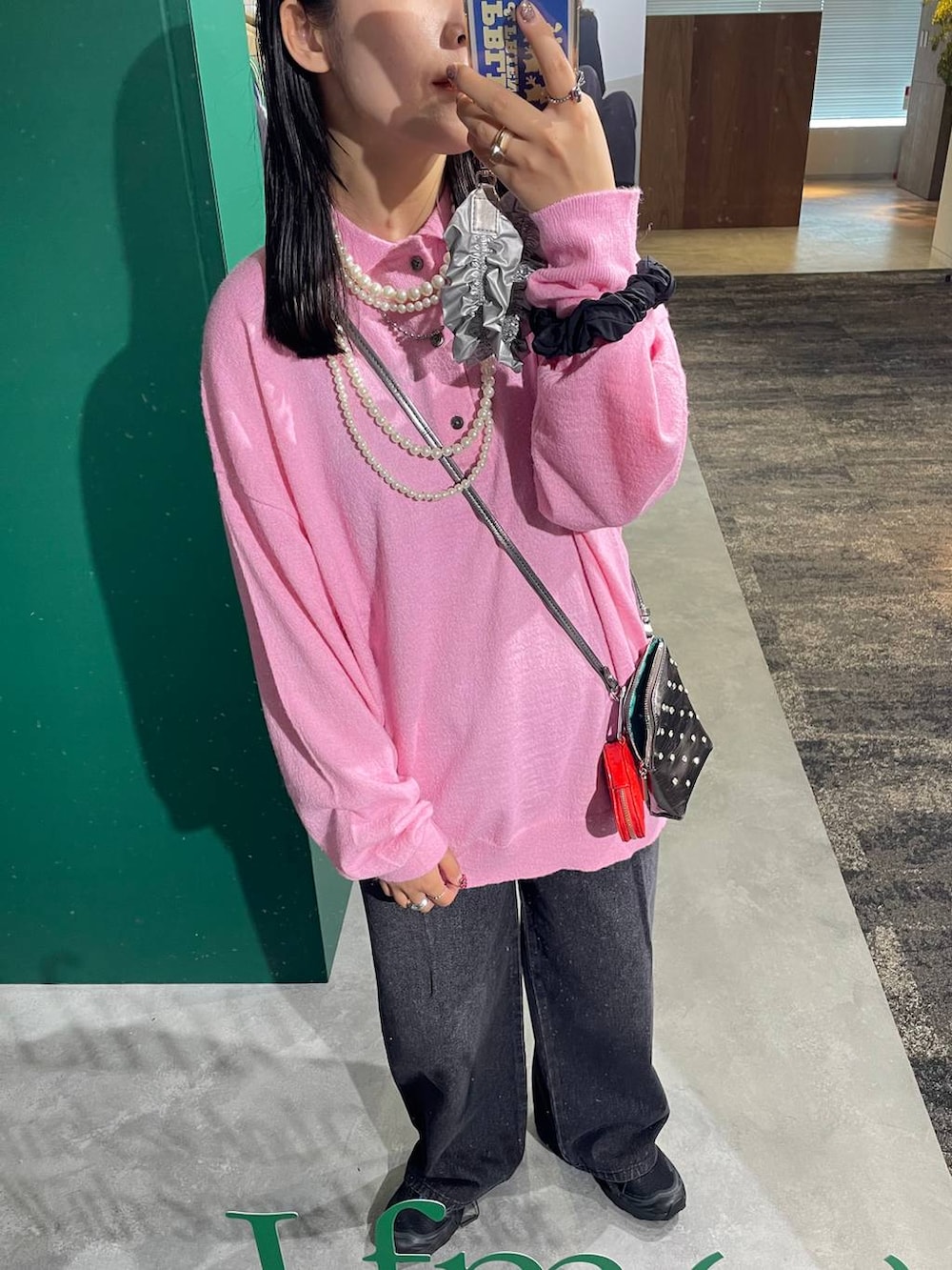 ブラック系のデニムパンツ、ピンク系のニット/セーター、ベージュ系のネックレスを着用したレディースの夏コーディネートの2枚目の写真