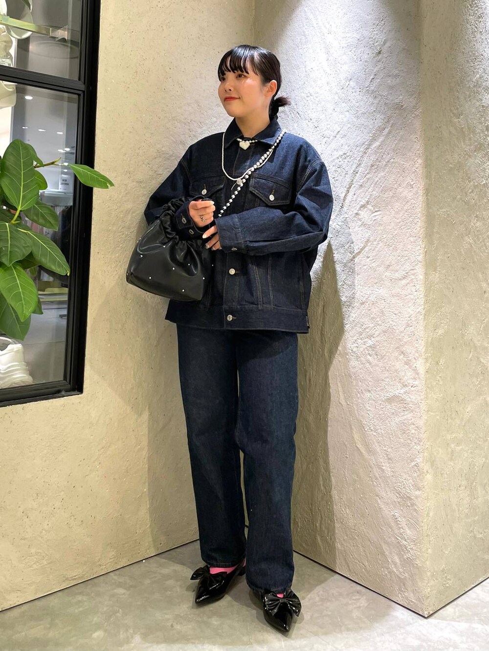 ブラック系のハンドバッグ、ブルー系のデニムパンツ、ブラック系のパンプスを着用したレディースの春コーディネートの3枚目の写真