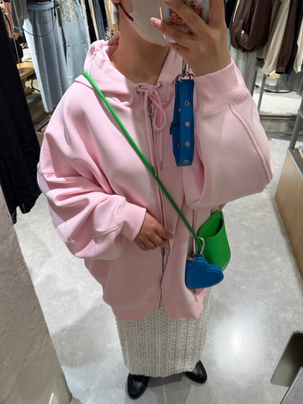 ピンク系のパーカー、ホワイト系のスカート、ブラック系のローファーを着用したレディースの冬コーディネートの2枚目の写真