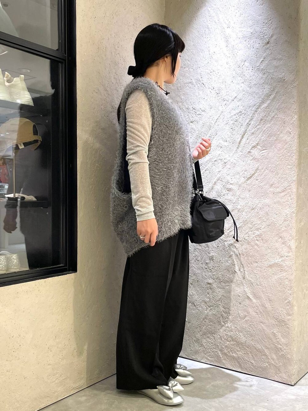 ブラック系のスラックス、グレー系のベスト、ブラック系のショルダーバッグを着用したレディースの秋コーディネートの4枚目の写真