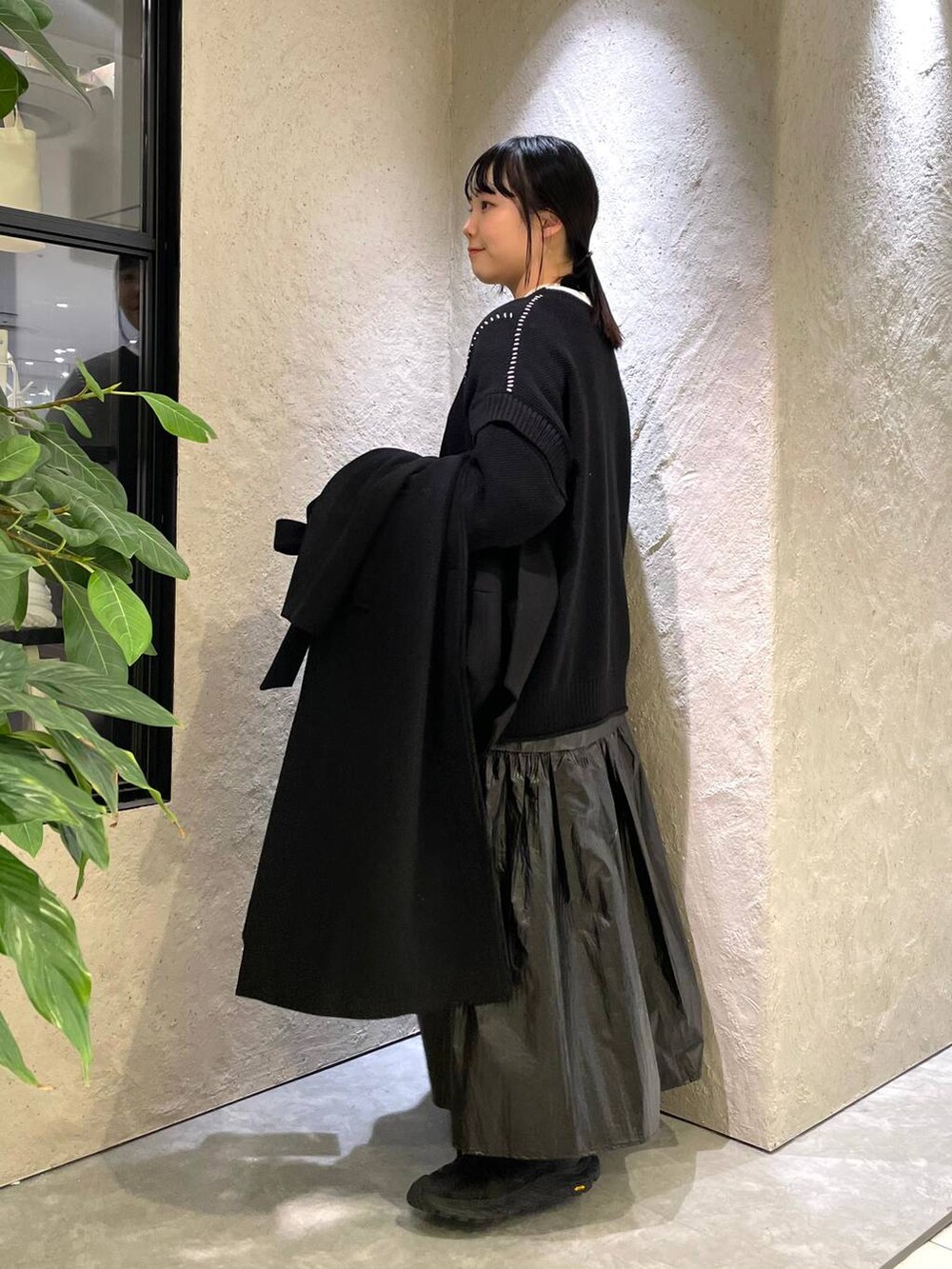 ブラック系のトレンチコート、ブラック系のTシャツ/カットソー、ブラック系のハンドバッグを着用したレディースの冬コーディネートの2枚目の写真