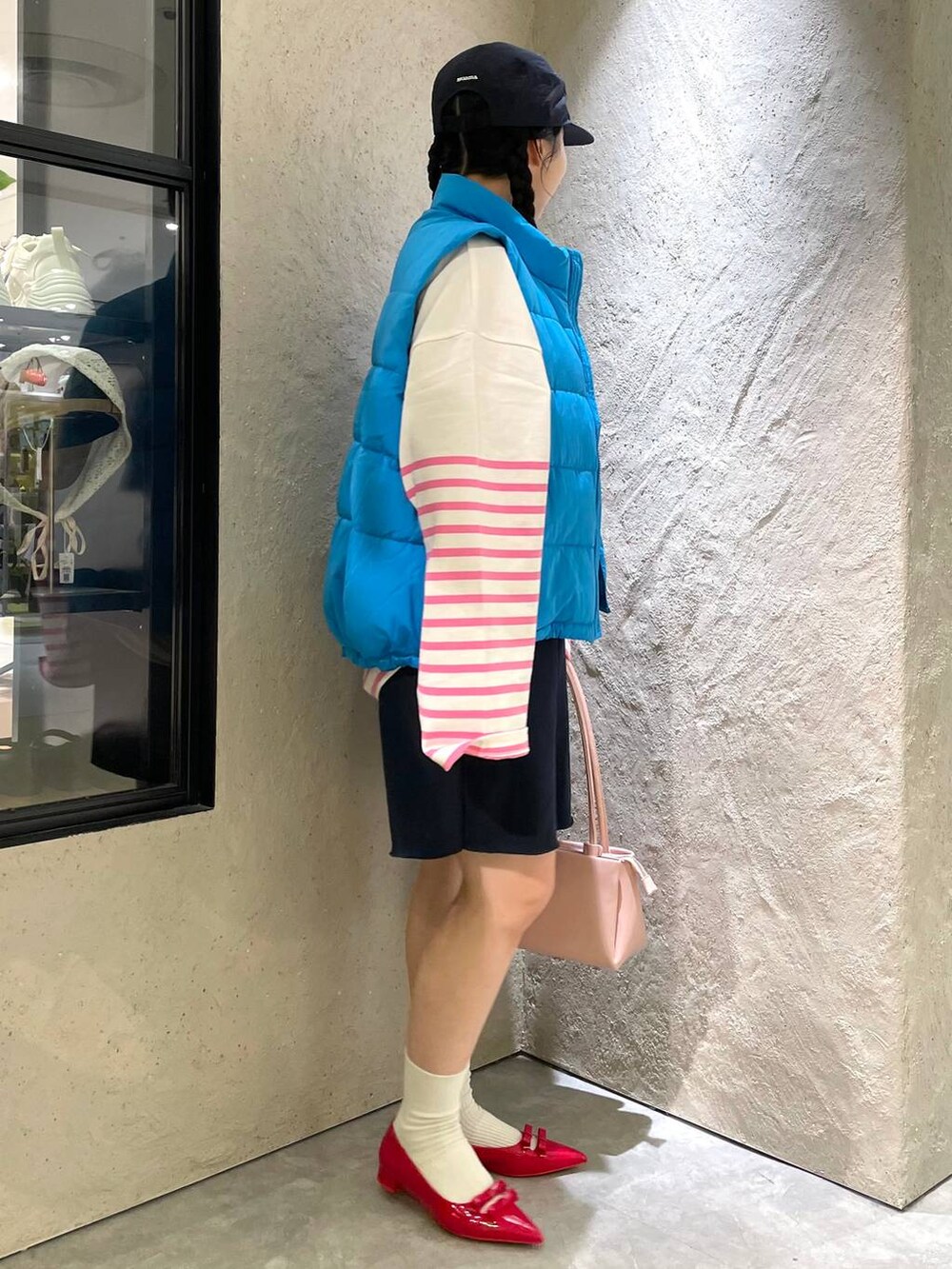 レッド系のパンプス、ブルー系のスウェットパンツ、ブルー系のダウンベストを着用したレディースの秋コーディネートの6枚目の写真