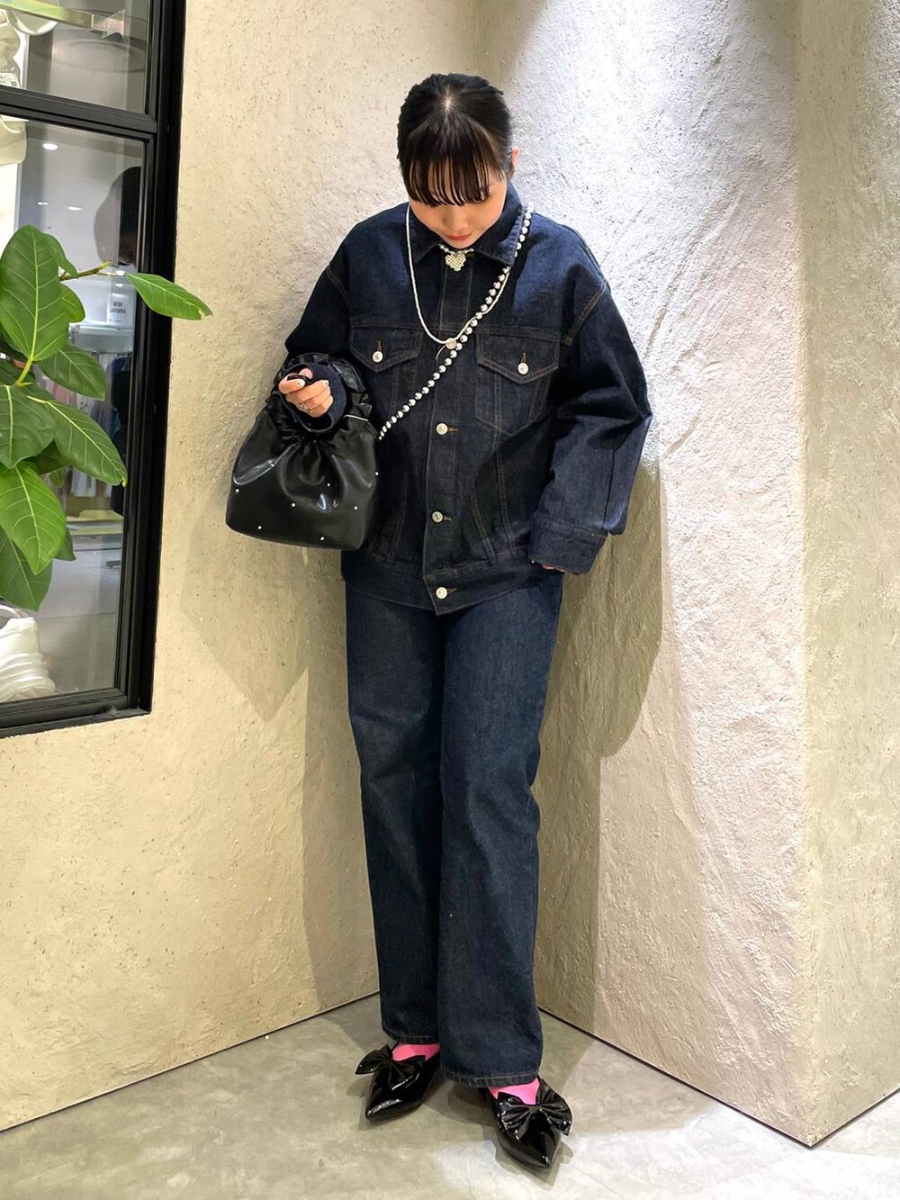 ブラック系のハンドバッグ、ブルー系のデニムパンツ、ブラック系のパンプスを着用したレディースの春コーディネートの7枚目の写真