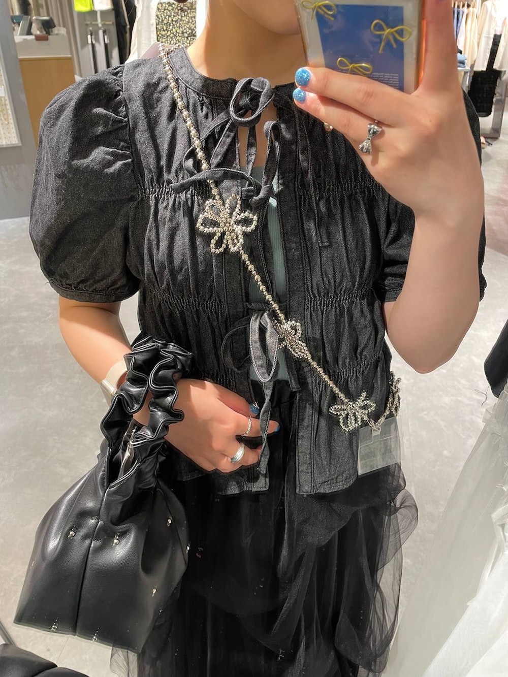 ブラック系のハンドバッグ、ブルー系のタンクトップ、ブラック系のバレエシューズを着用したレディースの春コーディネートの6枚目の写真