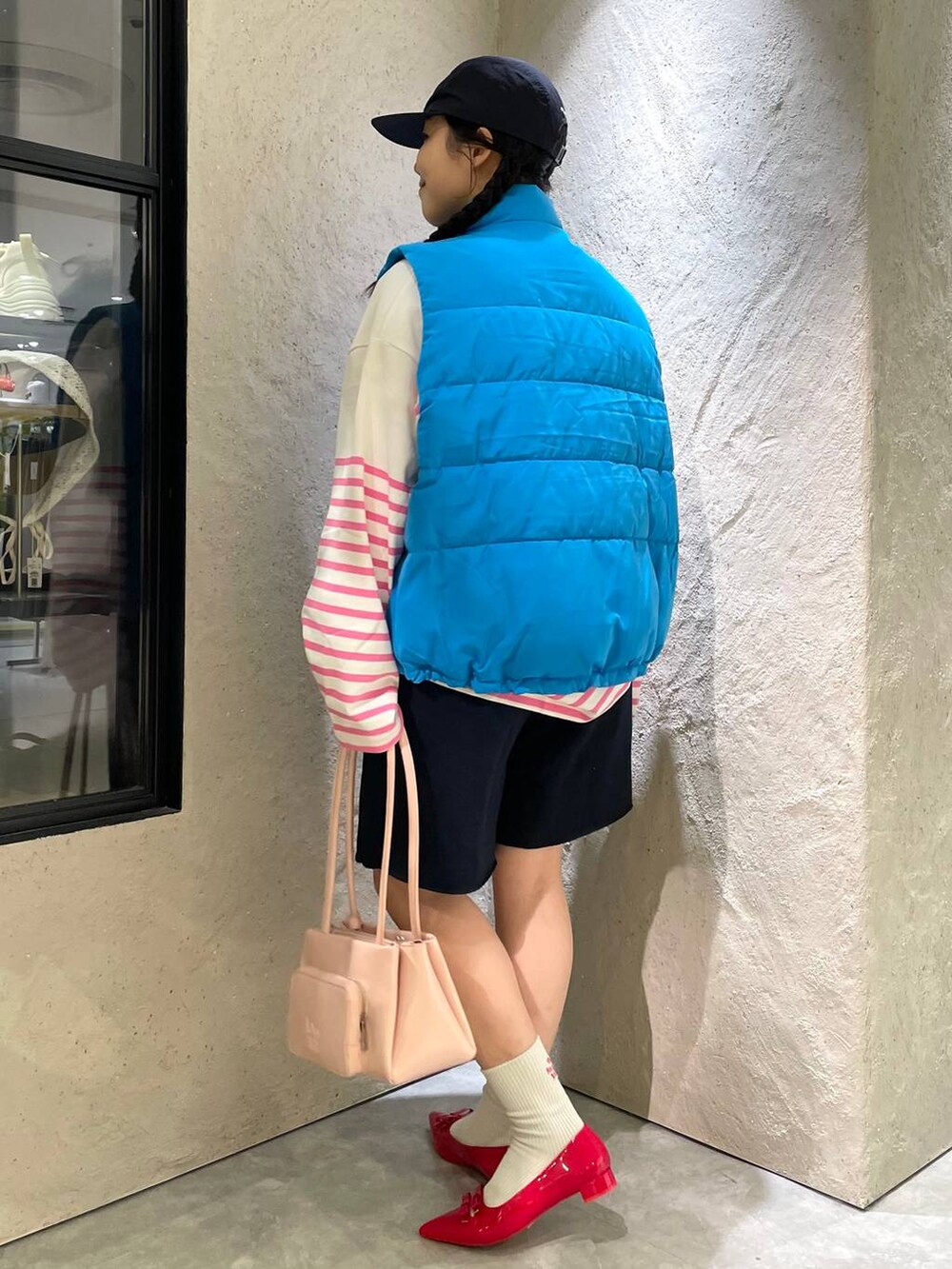 レッド系のパンプス、ブルー系のスウェットパンツ、ブルー系のダウンベストを着用したレディースの秋コーディネートの4枚目の写真