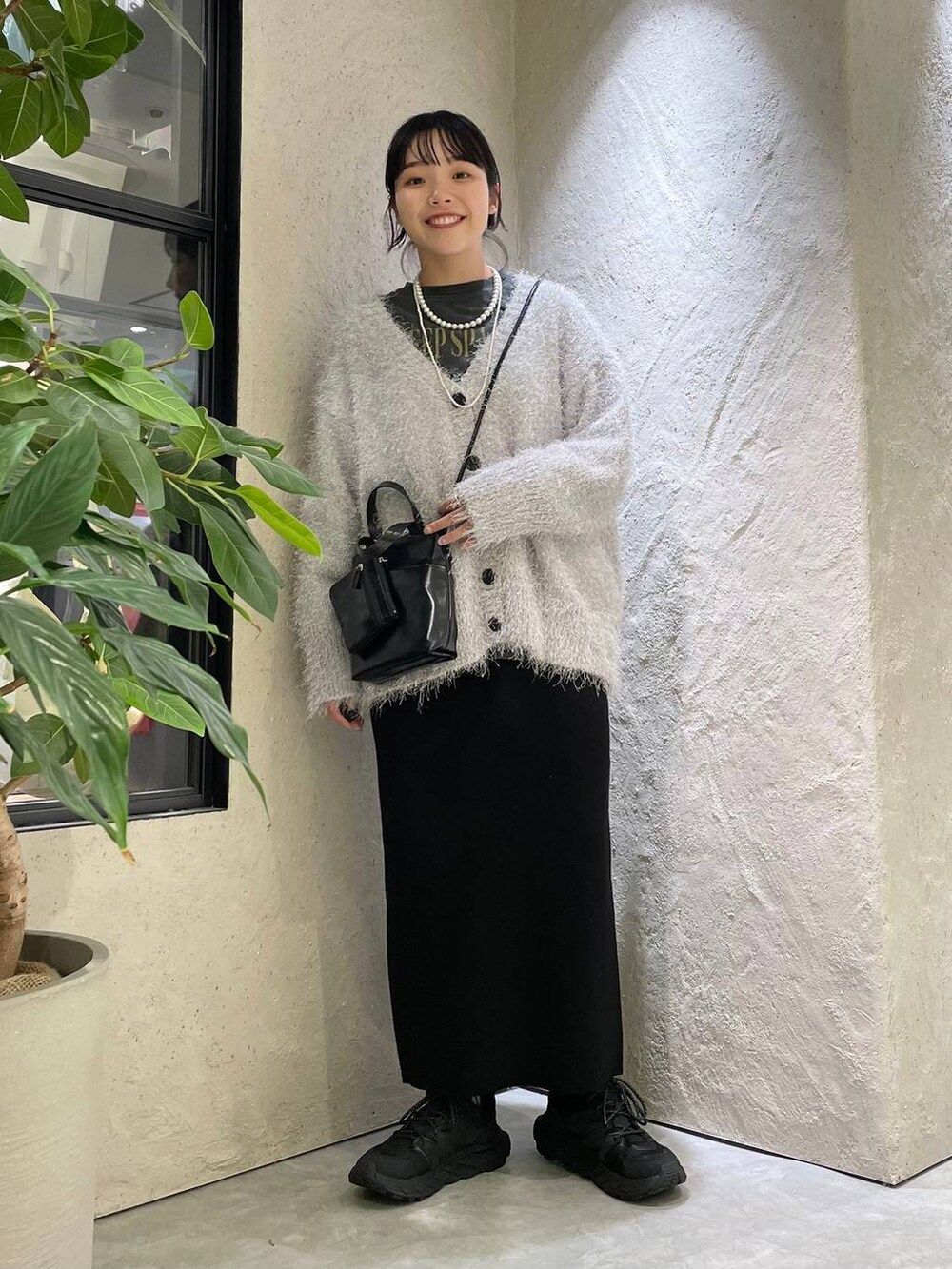 ブラック系のショルダーバッグ、グレー系のカーディガン/ボレロ、グレー系のTシャツ/カットソーを着用したレディースの秋コーディネートの2枚目の写真