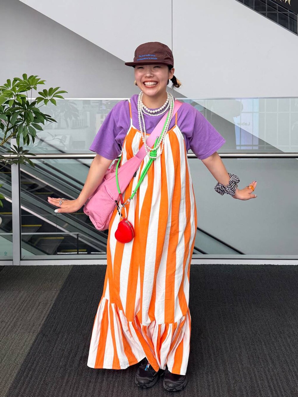 ピンク系のショルダーバッグ、ベージュ系のネックレス、ブラック系のシュシュを着用したレディースの夏コーディネートの3枚目の写真