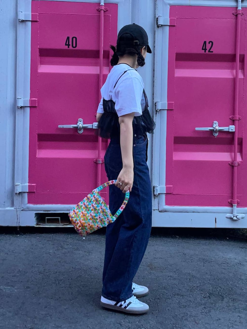 ホワイト系のスニーカー、ブラック系のベスト、ブルー系のデニムパンツを着用したレディースの夏コーディネートの4枚目の写真