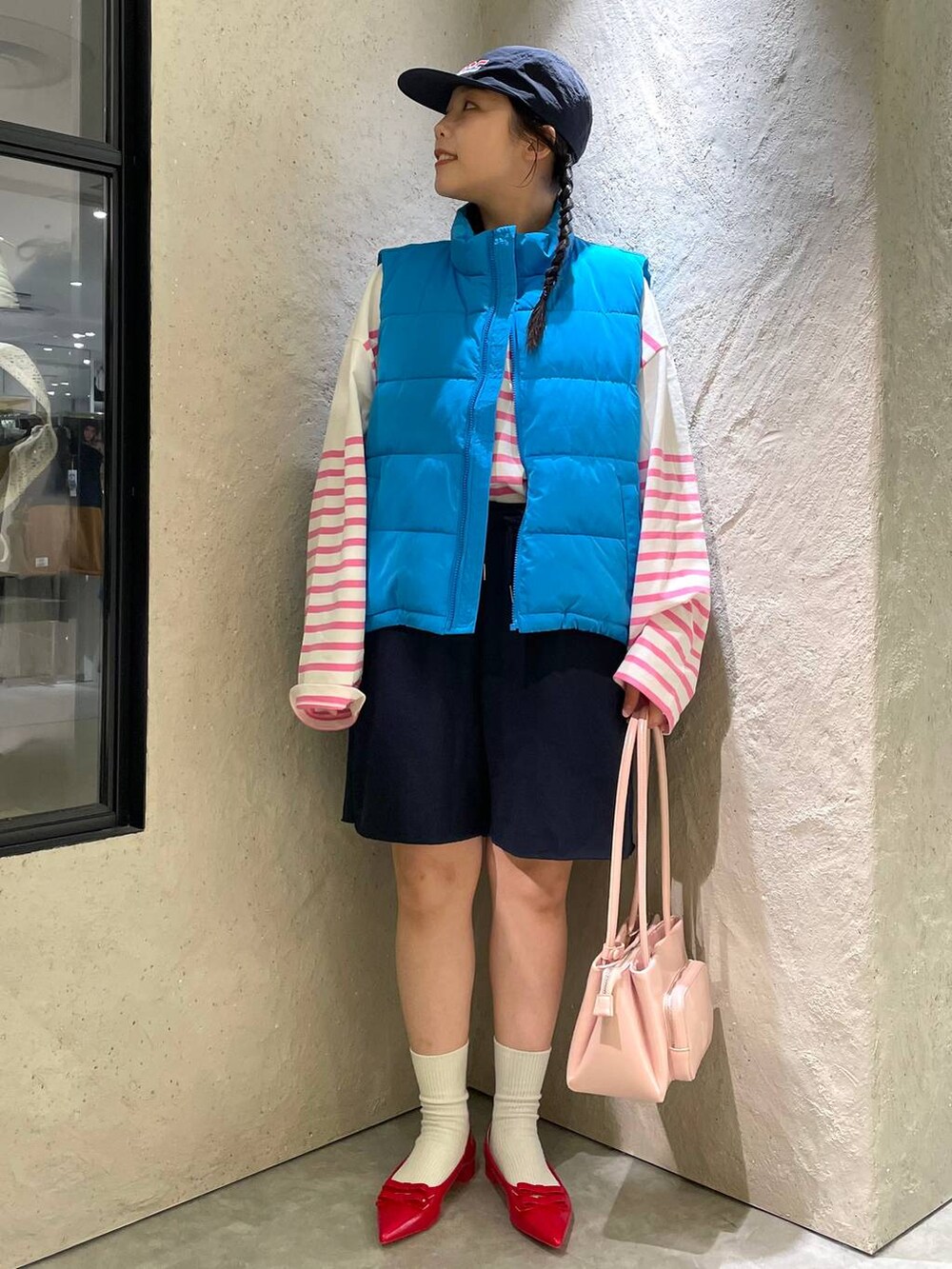 レッド系のパンプス、ブルー系のスウェットパンツ、ブルー系のダウンベストを着用したレディースの秋コーディネートの3枚目の写真