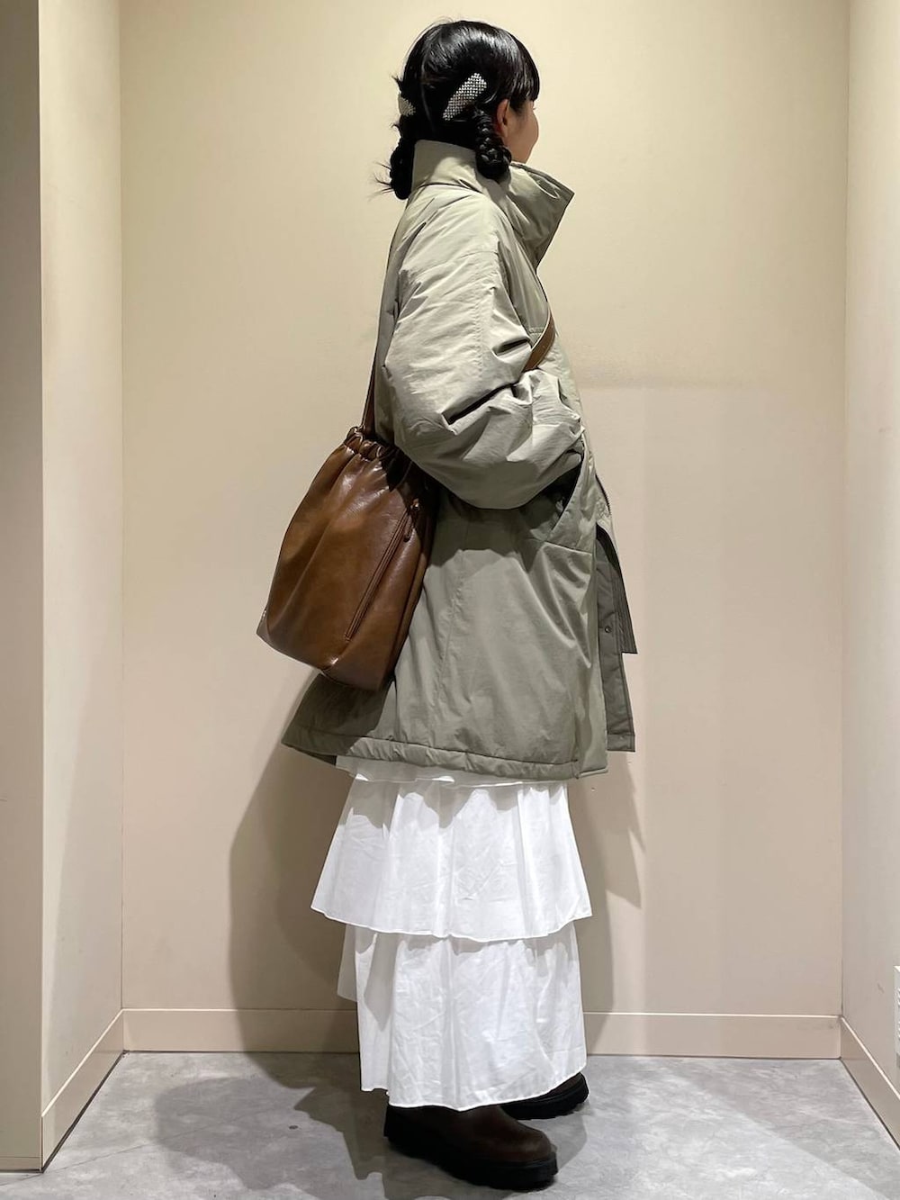 グリーン系のその他アウター、ブラウン系のブーツ、ホワイト系のスカートを着用したレディースの秋コーディネートの4枚目の写真