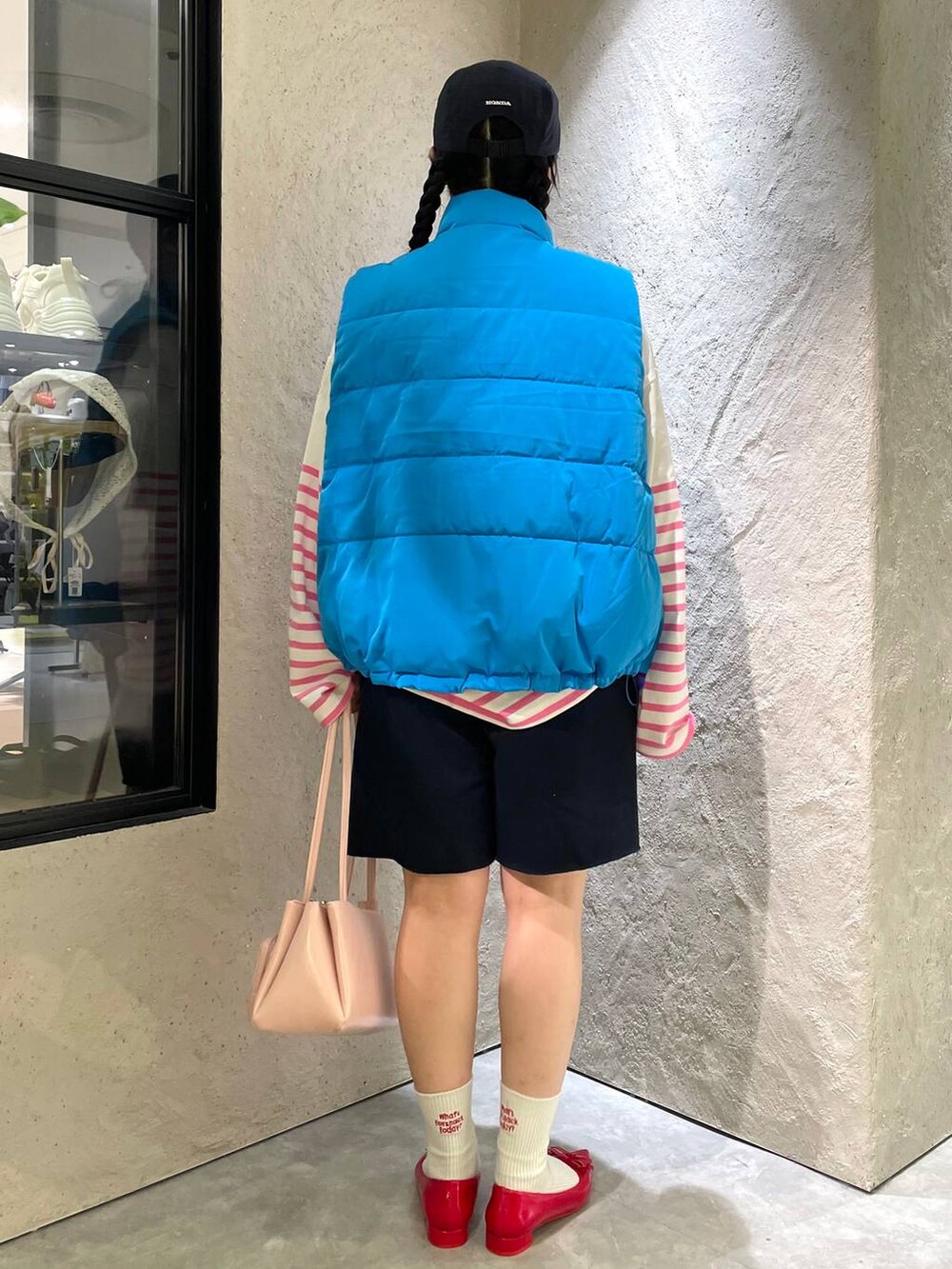 レッド系のパンプス、ブルー系のスウェットパンツ、ブルー系のダウンベストを着用したレディースの秋コーディネートの5枚目の写真