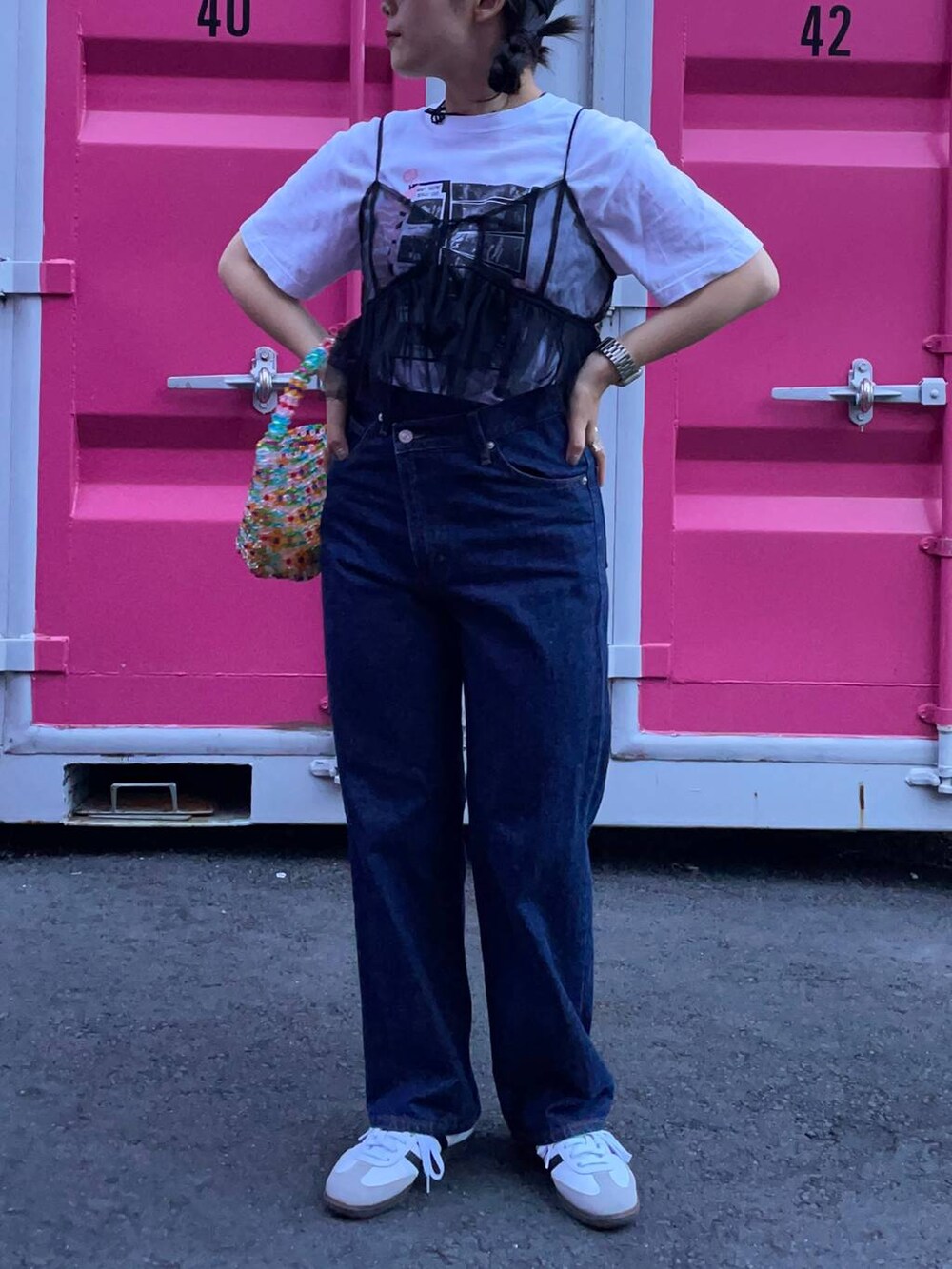 ホワイト系のスニーカー、ブラック系のベスト、ブルー系のデニムパンツを着用したレディースの夏コーディネートの5枚目の写真