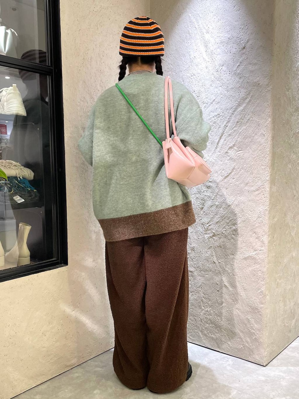 ブラック系のブーツ、ピンク系のショルダーバッグ、グリーン系のニット/セーターを着用したレディースの冬コーディネートの4枚目の写真