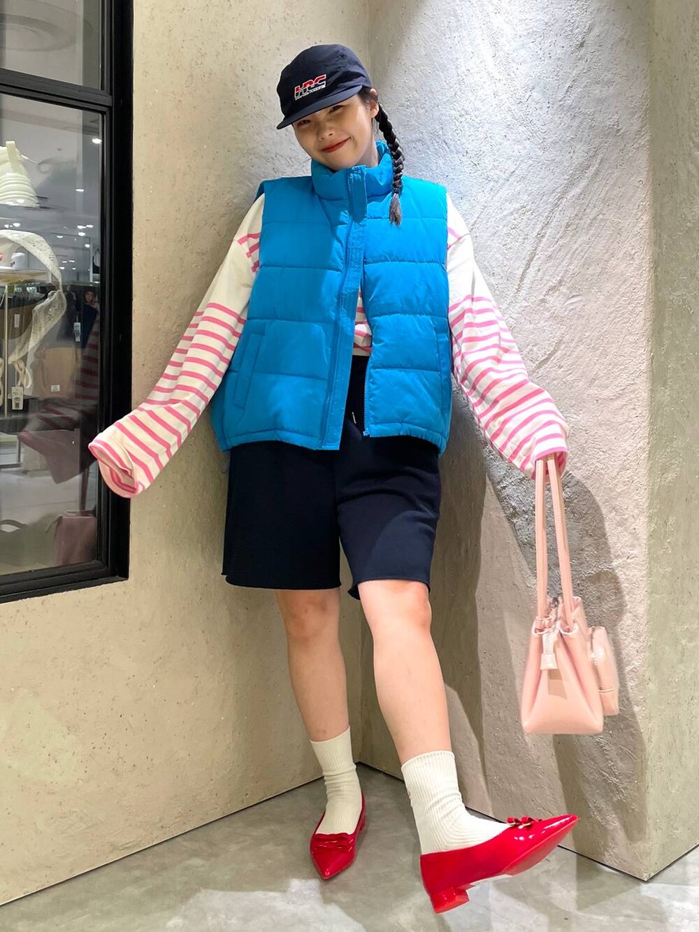 レッド系のパンプス、ブルー系のスウェットパンツ、ブルー系のダウンベストを着用したレディースの秋コーディネートの2枚目の写真
