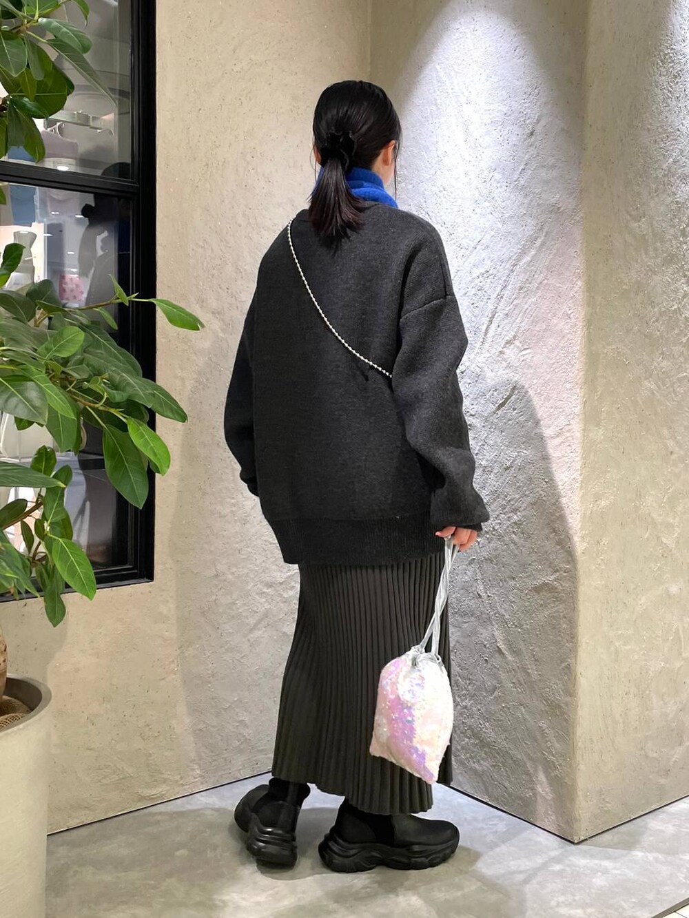 ホワイト系のハンドバッグ、グレー系のワンピース、ブラック系のブーツを着用したレディースの冬コーディネートの3枚目の写真