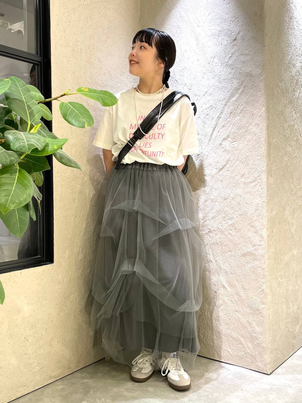グレー系のスカート、ホワイト系のTシャツ/カットソー、ブラック系のショルダーバッグを着用したレディースの夏コーディネートの2枚目の写真