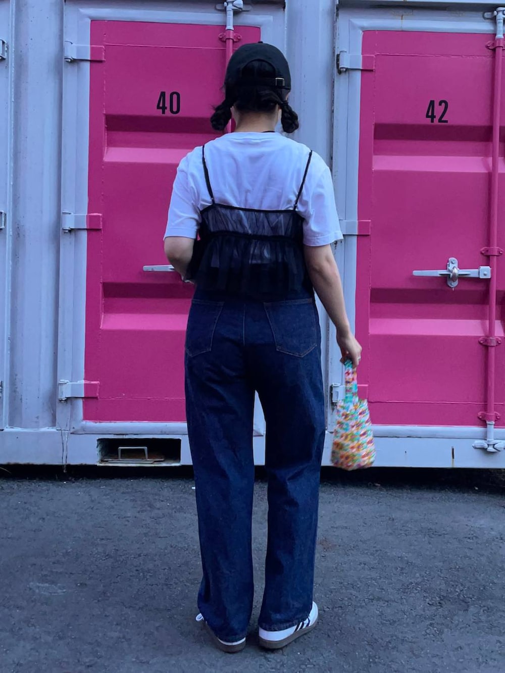 ホワイト系のスニーカー、ブラック系のベスト、ブルー系のデニムパンツを着用したレディースの夏コーディネートの3枚目の写真