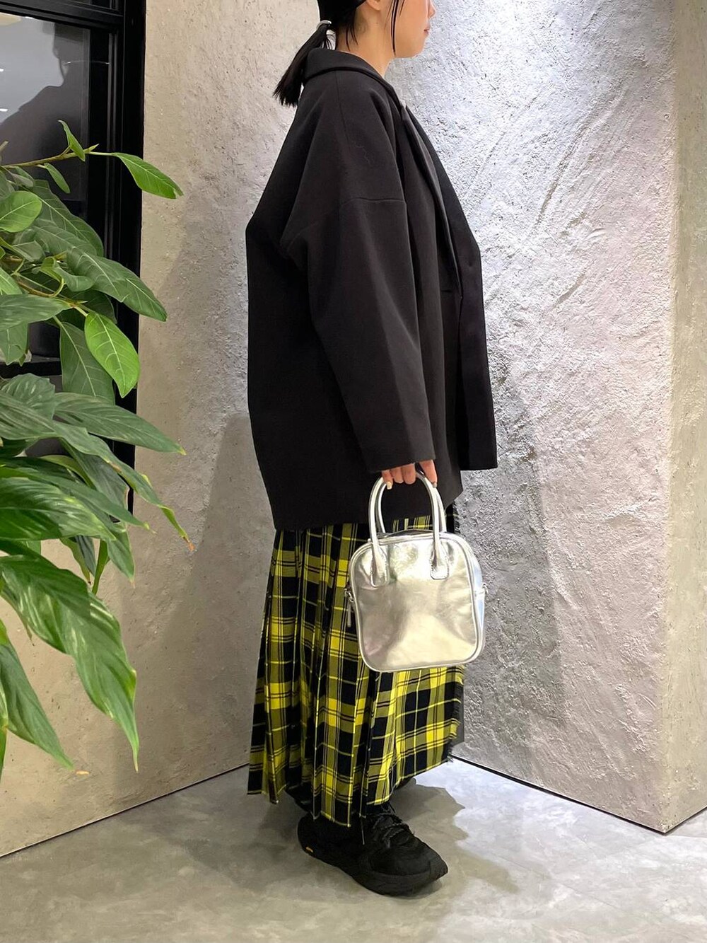 グレー系のステンカラーコート、グレー系のスウェット、イエロー系のスカートを着用したレディースの冬コーディネートの4枚目の写真