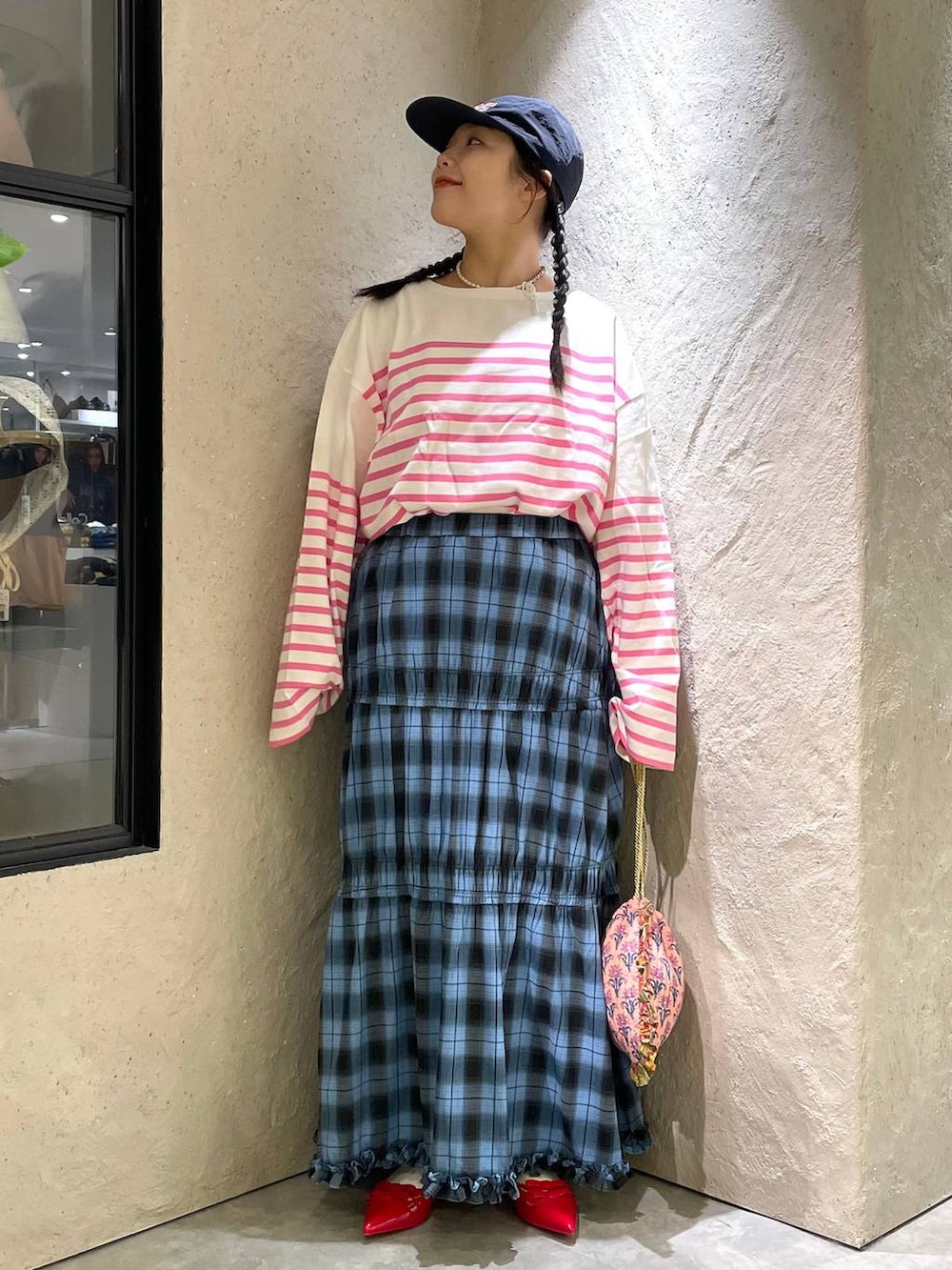 レッド系のパンプス、ピンク系のハンドバッグ、ブルー系のスカートを着用したレディースの秋コーディネートの2枚目の写真