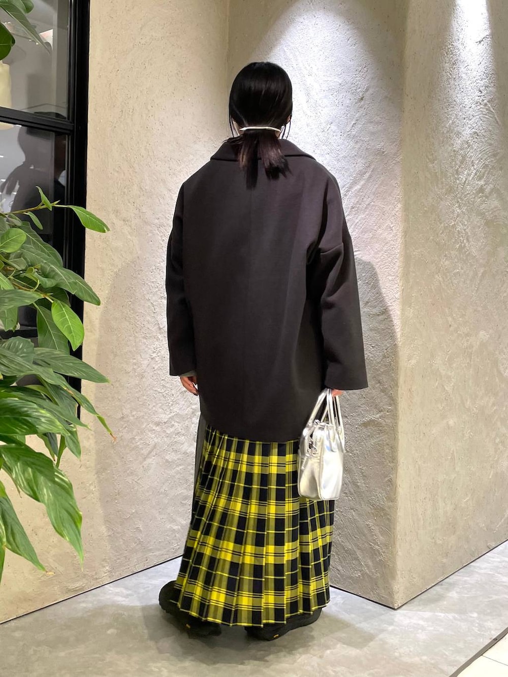 グレー系のステンカラーコート、グレー系のスウェット、イエロー系のスカートを着用したレディースの冬コーディネートの3枚目の写真