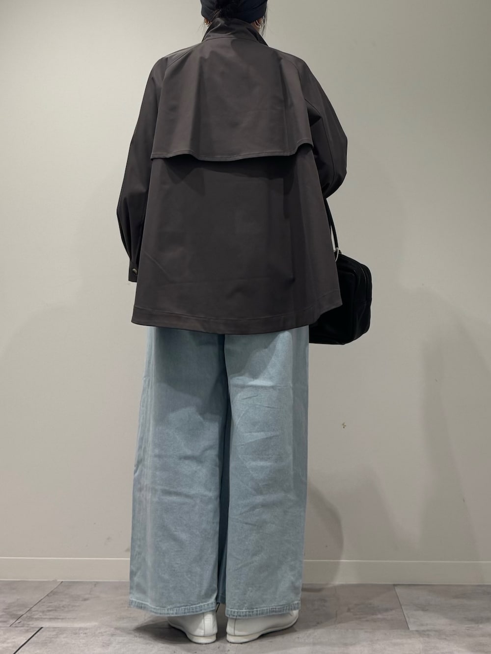 グレー系のトレンチコート、ブラック系のボストンバッグ、ブルー系のデニムパンツを着用したレディースの冬コーディネートの4枚目の写真