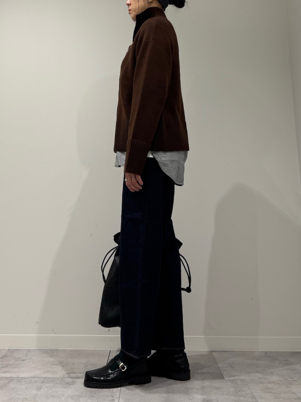 ブラック系のトートバッグ、ブルー系のデニムパンツ、ブラック系のローファーを着用したレディースの冬コーディネートの5枚目の写真