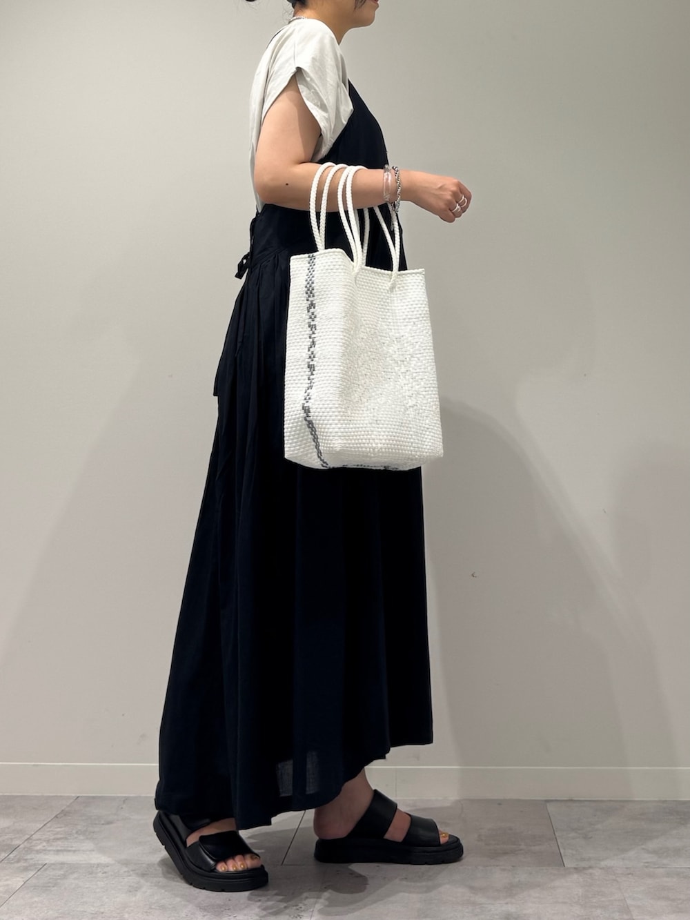 ブラック系のワンピース、ホワイト系のかごバッグ、ブラック系のサンダルを着用したレディースの夏コーディネートの2枚目の写真