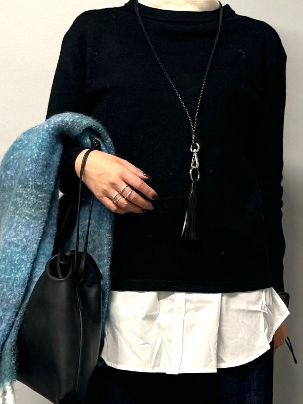 ブラック系のニット/セーター、ブルー系のデニムパンツ、ブラック系のショルダーバッグを着用したレディースの秋コーディネートの2枚目の写真