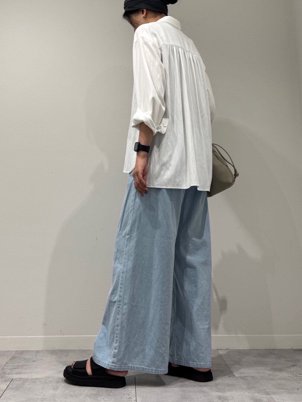 ベージュ系のショルダーバッグ、ブルー系のデニムパンツ、ブラック系のサンダルを着用したレディースの秋コーディネートの5枚目の写真